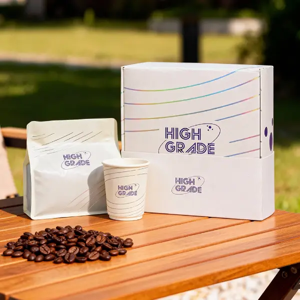 Scatola da caffè personalizzata con sacchetto da caffè abbinato e bicchiere di carta esposti all'aperto su un tavolo di legno