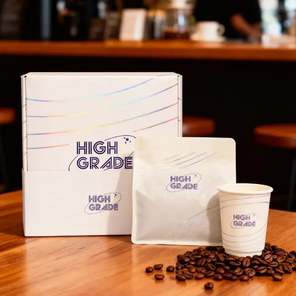 Scatola da caffè personalizzata di marca premium esposta con una busta e una tazza in un ambiente da caffè