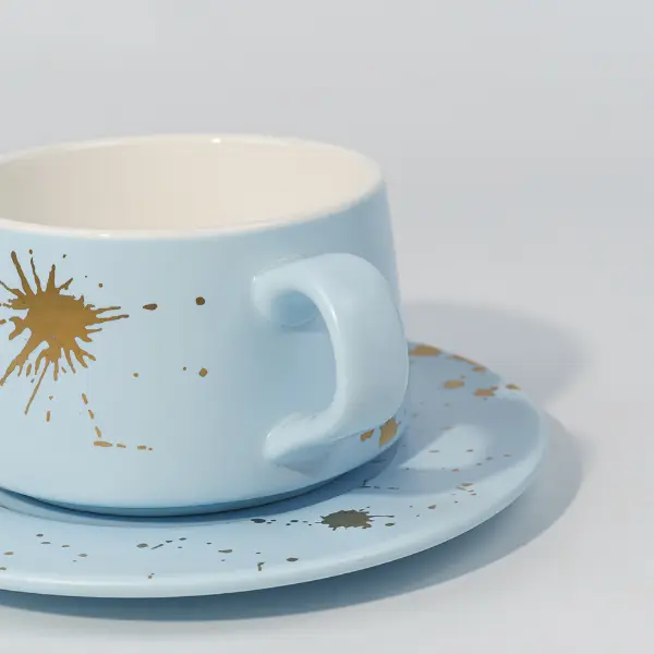 Dettaglio del manico in ceramica della tazza da caffè con decorazione a schizzi di foglia d'oro