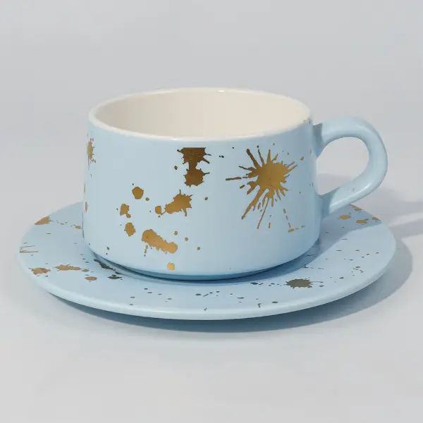Vista laterale di tazza da caffè in ceramica in foglia d'oro con motivo a schizzi dipinti a mano
