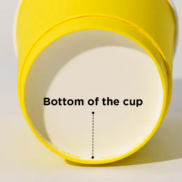 Primo piano della struttura inferiore di un bicchiere di carta giallo che mostra il design della base del bicchiere