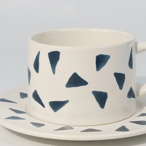 Vista laterale di una tazza da caffè in ceramica stampata con manico e motivo stampato