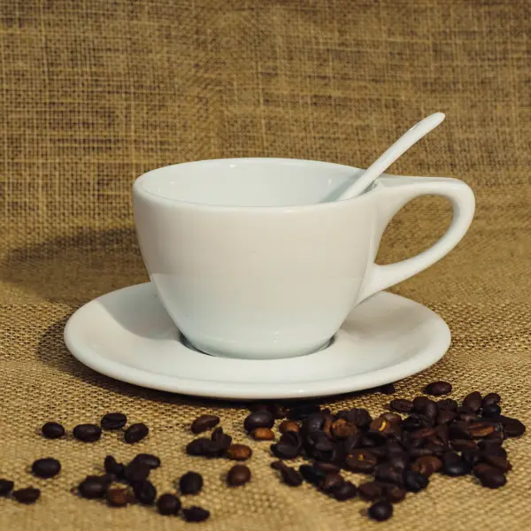 Tazza da caffè in ceramica bianca con coperchio piatto e manico esposto con chicchi di caffè