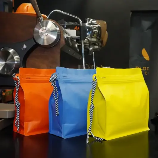 I sacchetti da caffè personalizzati con cordino non sono più un formato di nicchia in 2026. Sono diventati pratici, Scelta di confezionamento ad alto volume per chicchi sfusi e caffè macinato—soprattutto quando i marchi hanno bisogno sia di forza operativa che di una pulizia, Aspetto pronto per il commercio. At YPAK, Trattiamo il cordone come qualcosa di più di una cinghia. Usato correttamente, diventa un punto di maneggevolezza funzionale e un segnale visivo di durabilità, Il che può influenzare il modo in cui gli acquirenti valutano la qualità in pochi secondi. Il packaging in grandi quantità presenta una sfida costante: Deve lavorare sodo nel retro, eppure rappresentano comunque il marchio in sala. Questo significa stabilità, Richiusura affidabile, Gestione del gas, e comodità di maneggevolezza. Quando quegli elementi si uniscono, La busta smette di essere 
